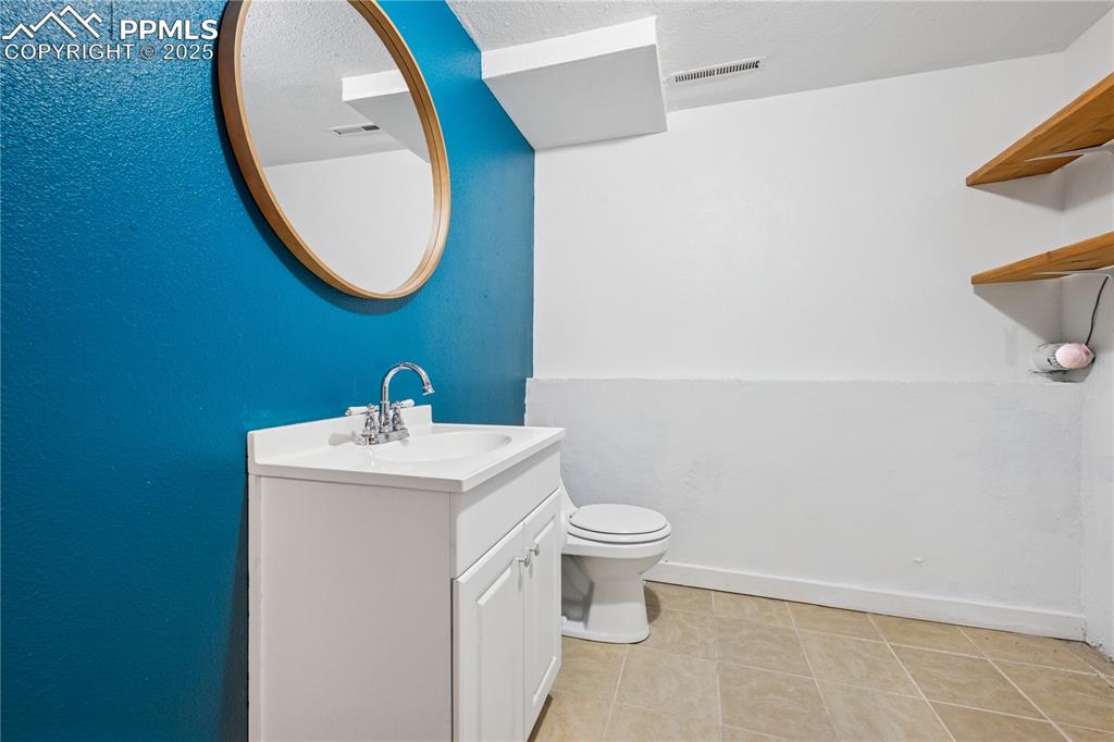 Image 33 of 35: Bathroom with vanity, light tile patterned floors, and a textured ceiling. 