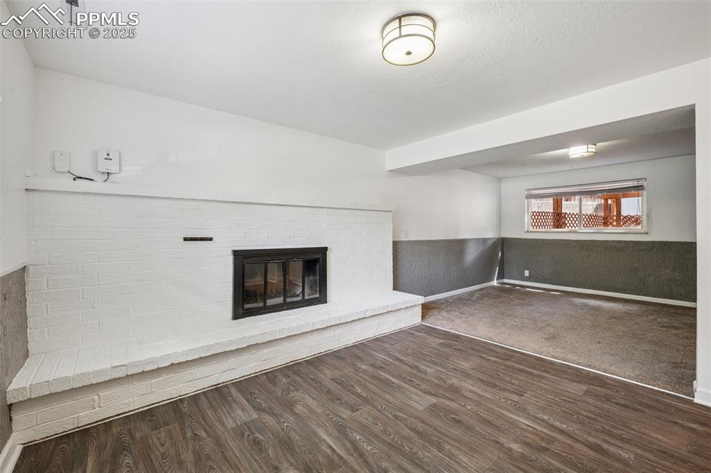 Image 35 of 35: Unfurnished living room featuring a brick fireplace, dark wood-style floors