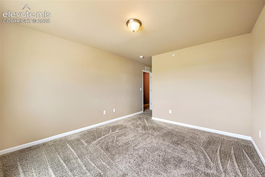 Image 11 of 25: Owners Bedroom - Carpeted room with neutral-toned walls, white baseboards, 