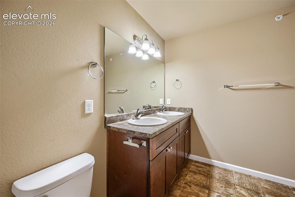 Image 14 of 25: Bathroom featuring a dual vanity with a dark wood-finish cabinet and integr