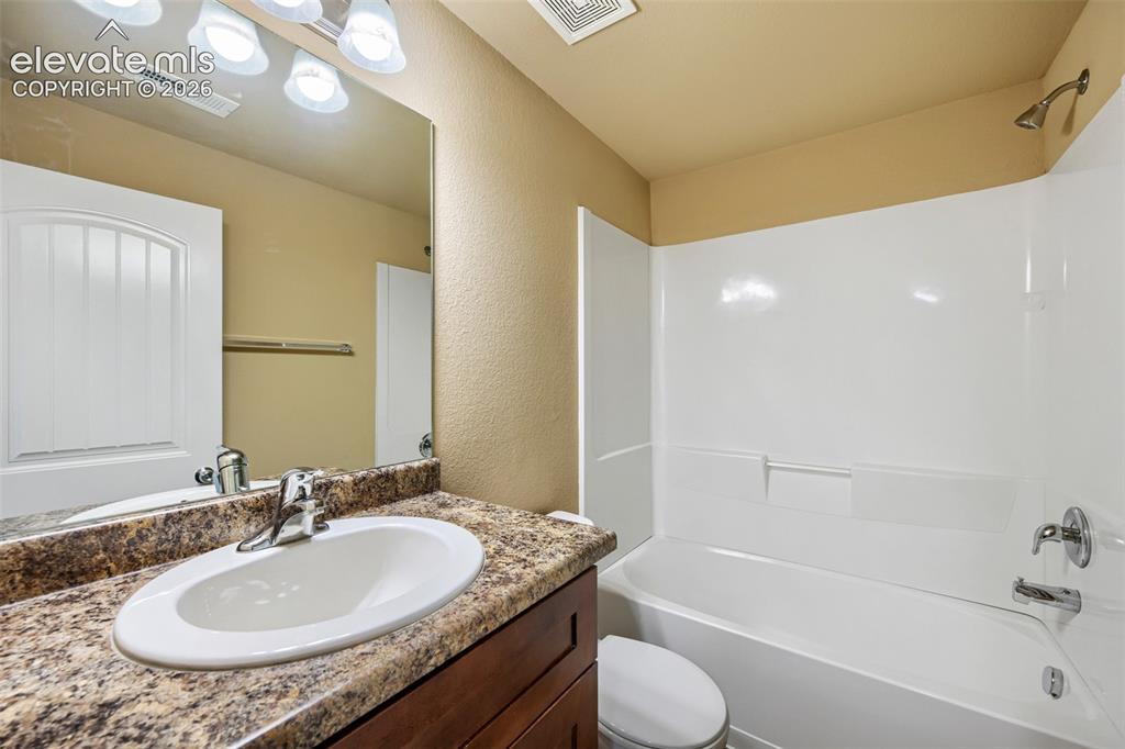 Image 21 of 25: Basement Bathroom featuring a wood-finish vanity with a stone-look countert