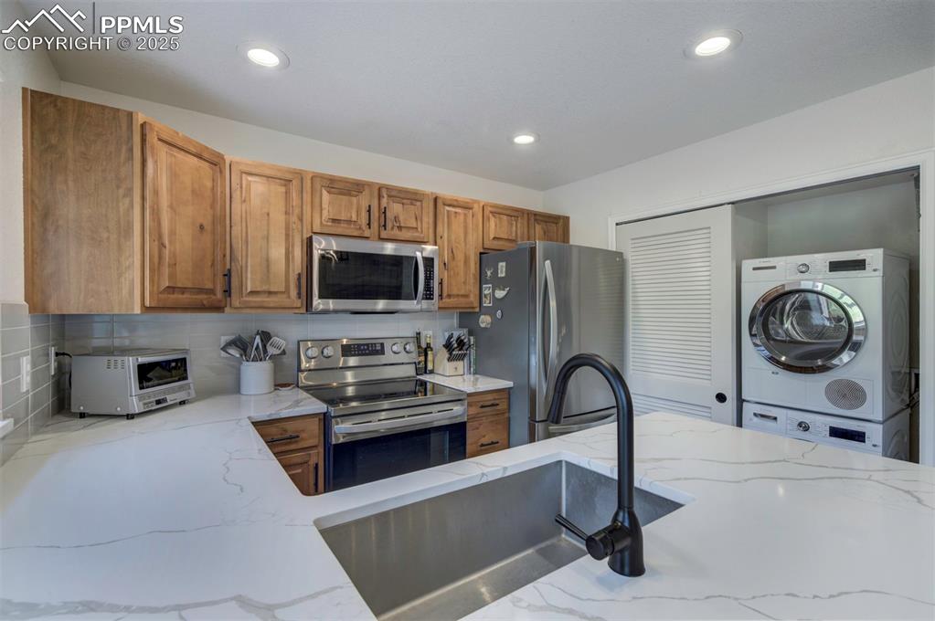 Image 11 of 30: Kitchen with appliances with stainless steel finishes, brown cabinets, ligh
