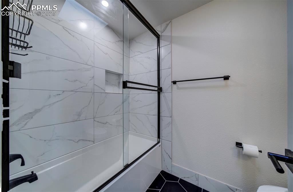 Image 14 of 30: Full bath with shower / bath combination with glass door and a textured wal