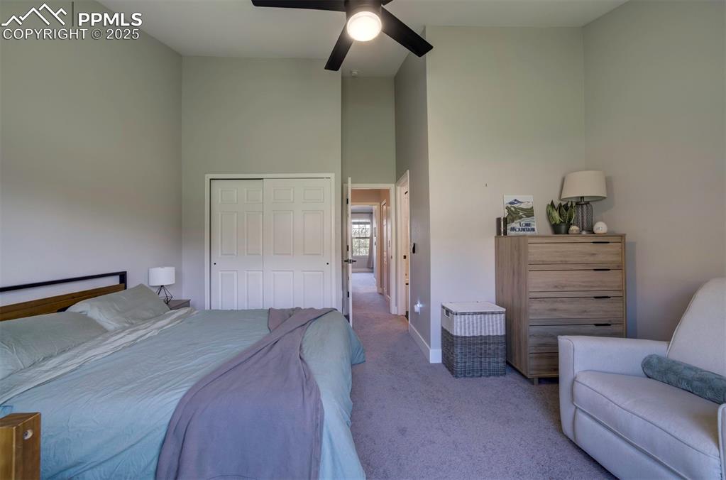 Image 18 of 30: Bedroom with carpet flooring, a high ceiling, a closet, and a ceiling fan