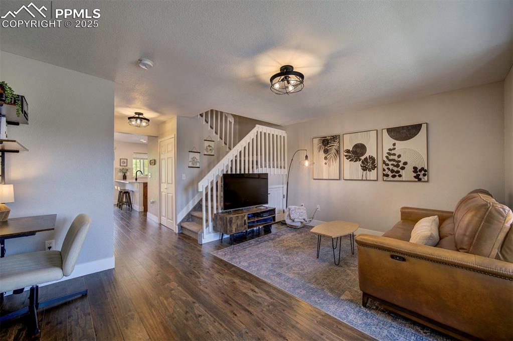 Image 2 of 30: Living area featuring stairway and dark wood-type flooring