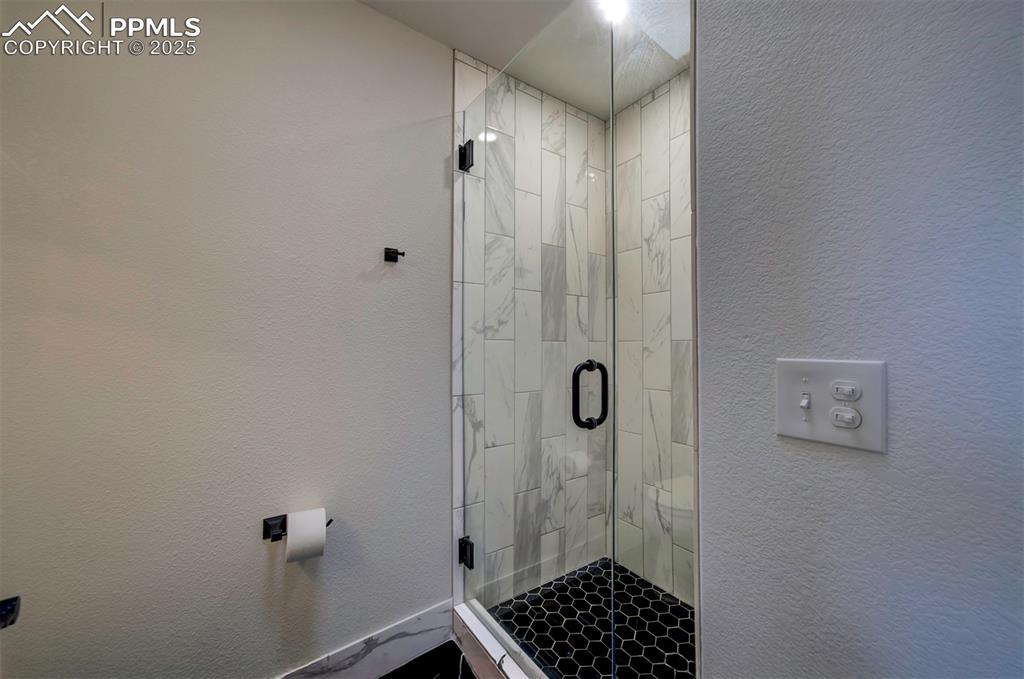 Image 22 of 30: Full bath featuring a textured wall and a stall shower