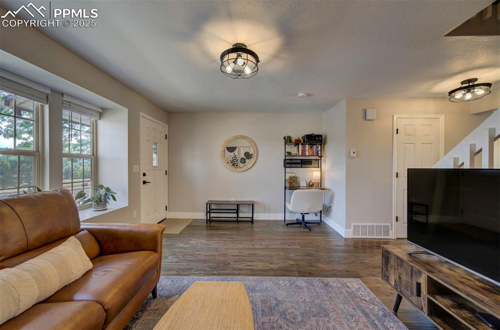 Image 4 of 30: Living room with dark wood-type flooring and a textured ceiling