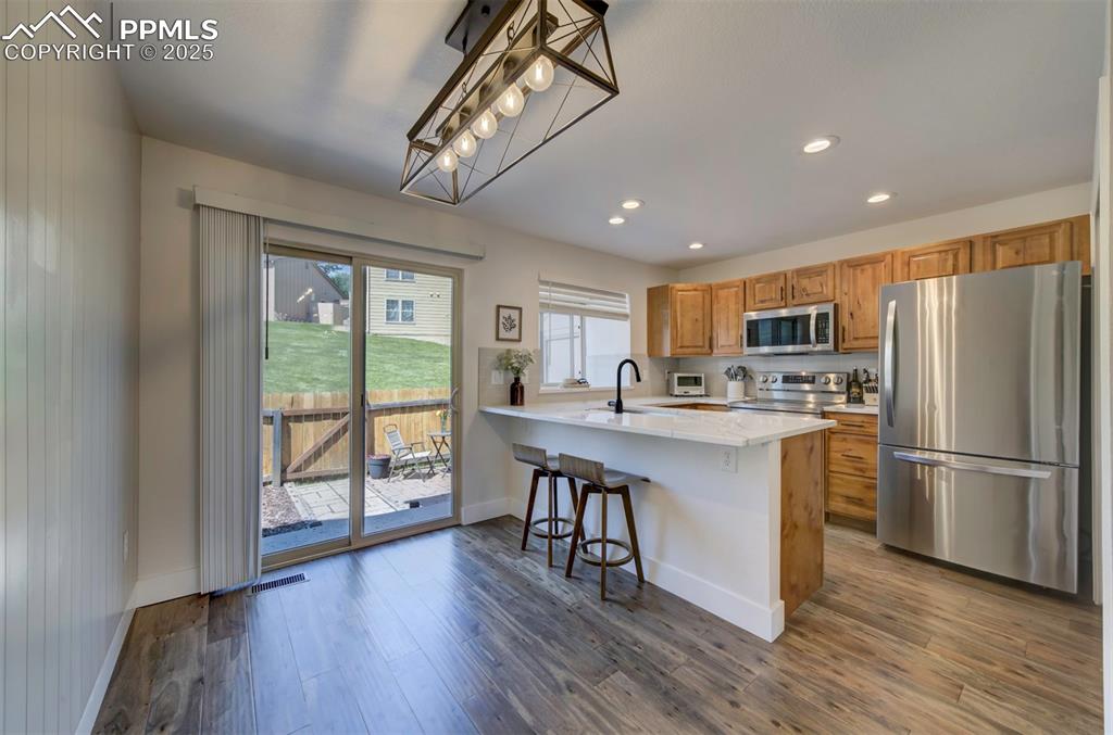 Image 6 of 30: Kitchen with appliances with stainless steel finishes, a breakfast bar area