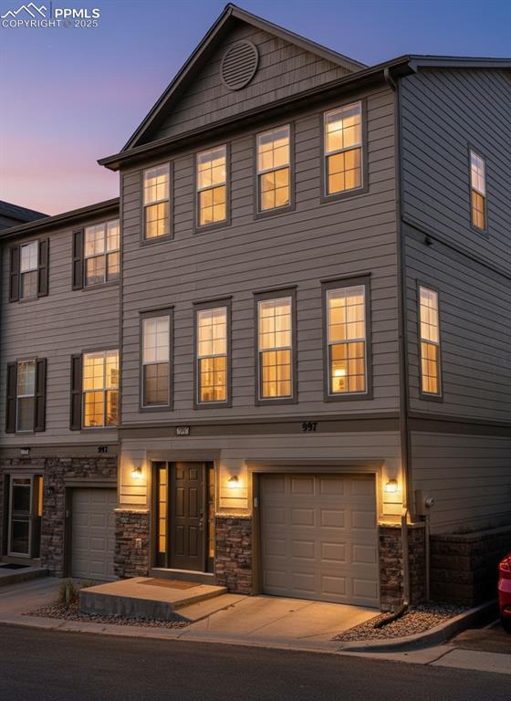 Caption: View of front of property featuring stone siding and a garage