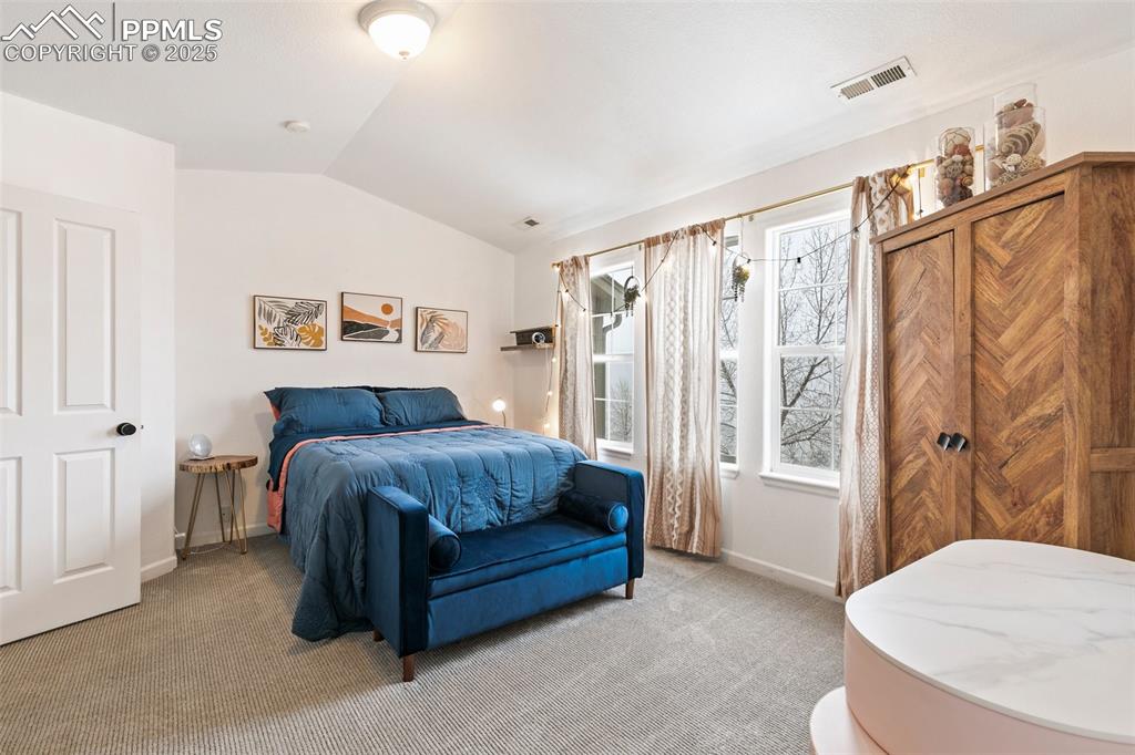 Image 24 of 36: Bedroom featuring lofted ceiling, light carpet, and baseboards