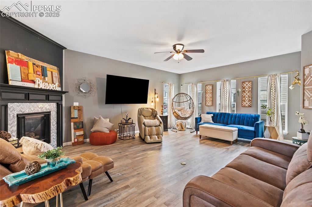 Image 3 of 36: Living area featuring ceiling fan, a tile fireplace, wood finished floors,