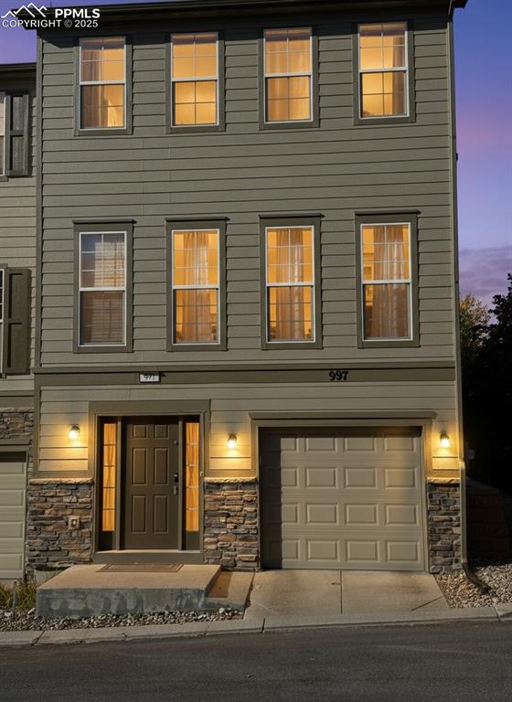 Image 35 of 36: View of front of home featuring stone siding and an attached garage
