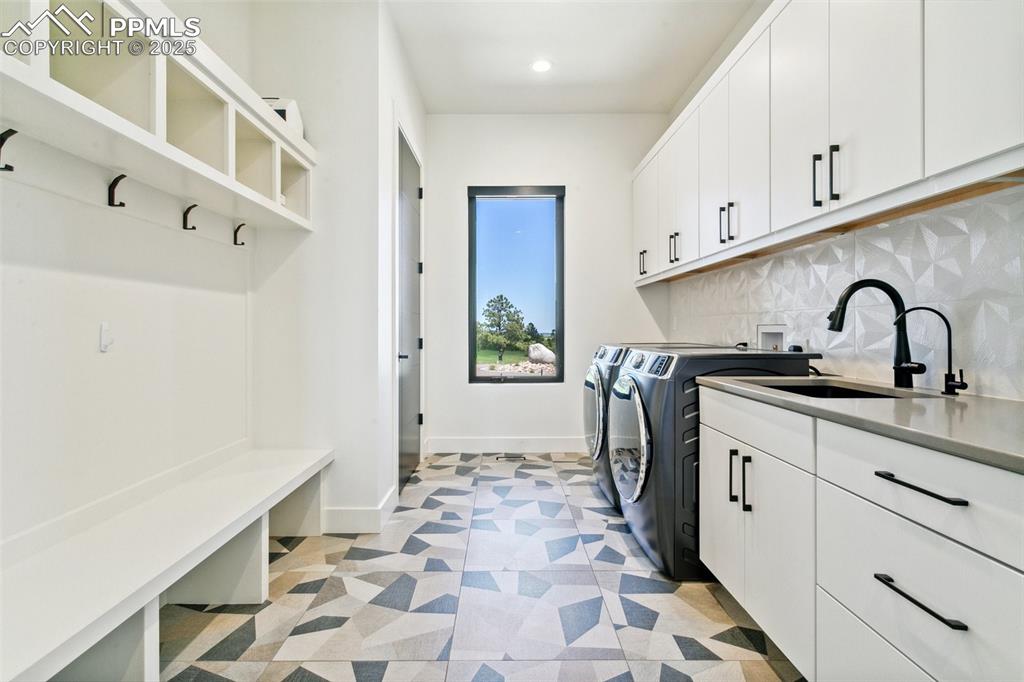Image 23 of 50: Large drop zone area in from garage with two closets and utility sink
