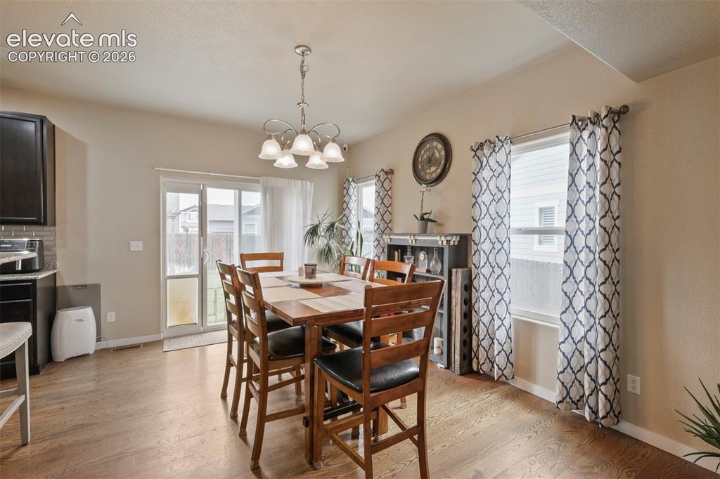 Image 11 of 33: Dining area with wood-finish flooring and a contemporary chandelier