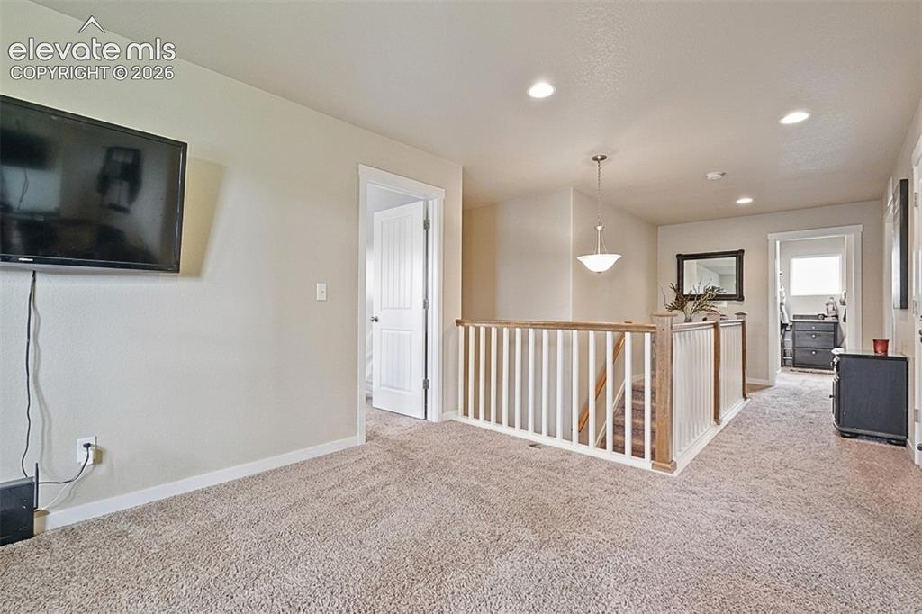 Image 19 of 33: Upper Level: Carpeted landing with white balusters and a wood-finish handra