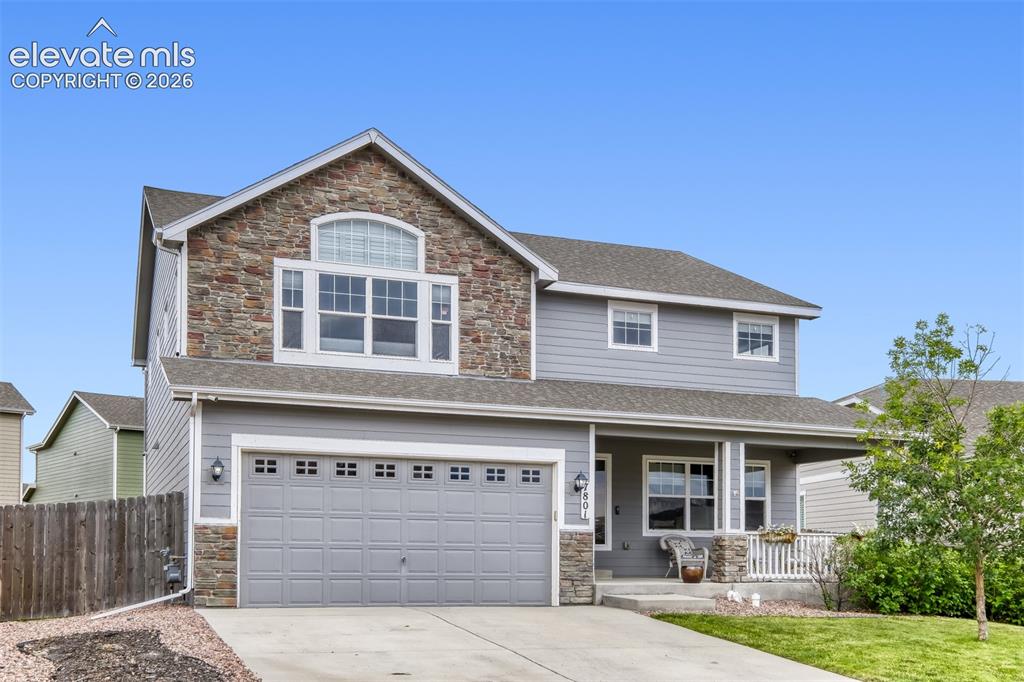 Image 2 of 33: Two-story residence featuring a stone and siding facade, an attached two-ca