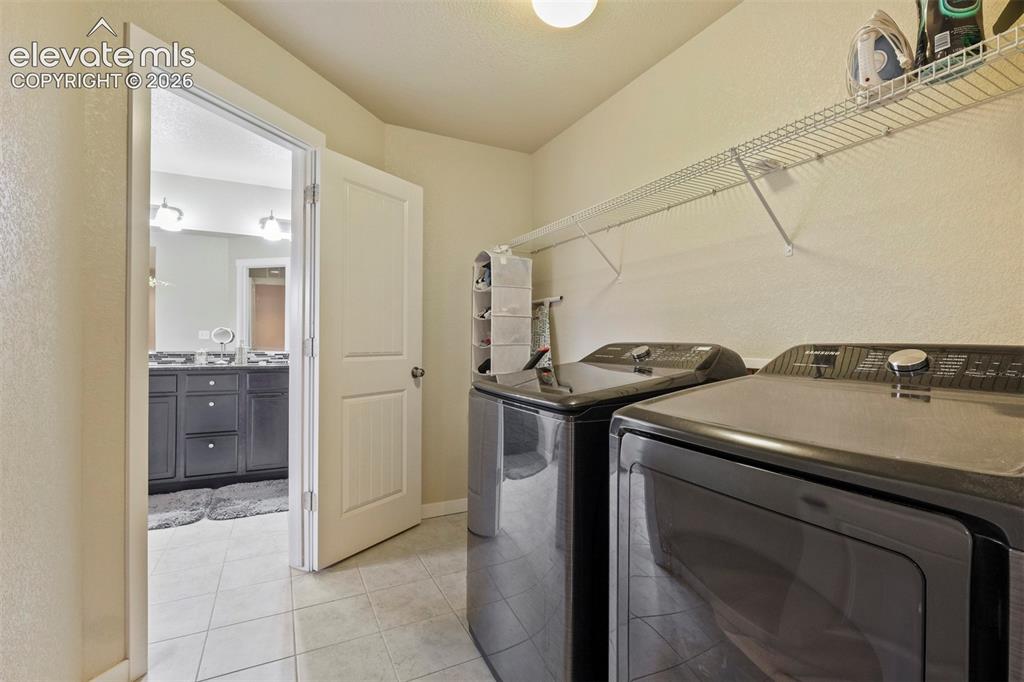 Image 23 of 33: Upper Level: Dedicated laundry area featuring tile flooring and overhead wi