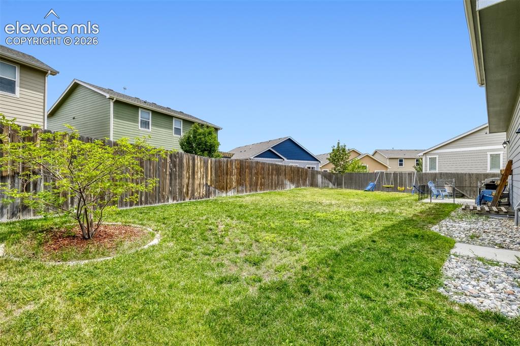 Image 28 of 33: Expansive backyard featuring a manicured lawn, full privacy fencing, and a 