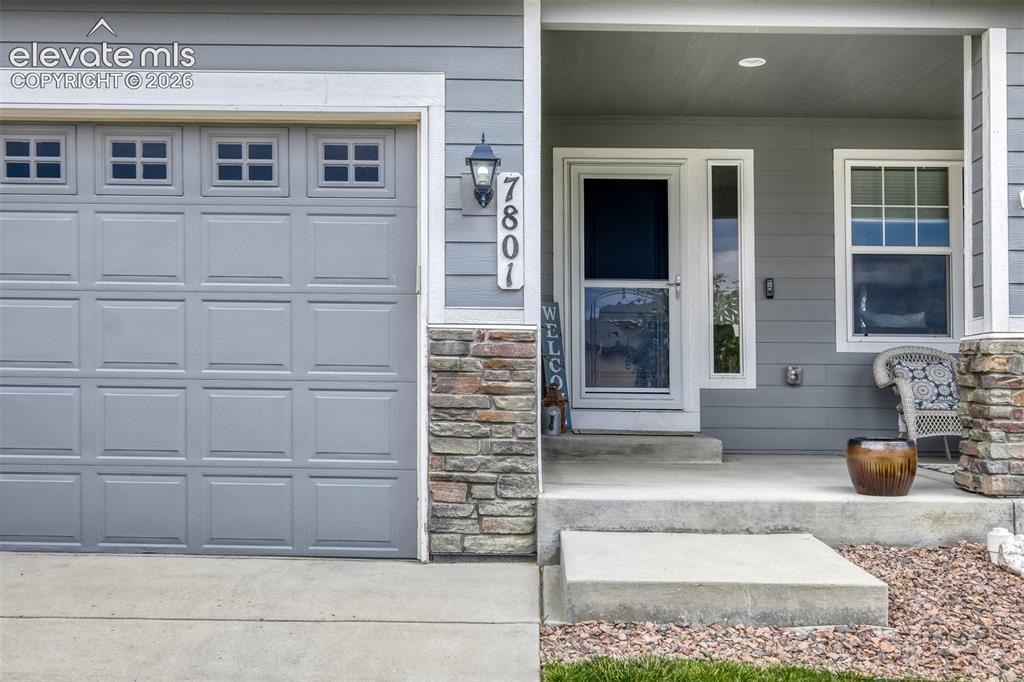 Image 3 of 33: Exterior featuring light gray siding with stone accents, a paneled garage d