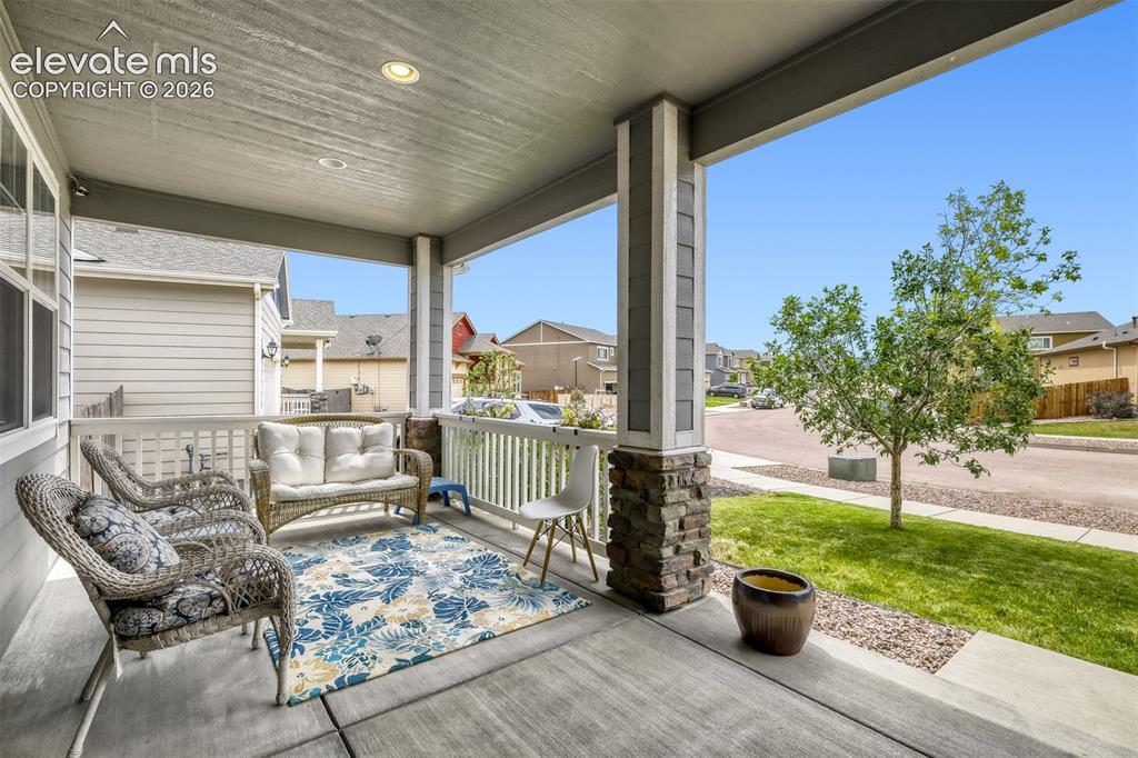 Image 4 of 33: Covered front porch featuring a stone and siding column, concrete flooring,