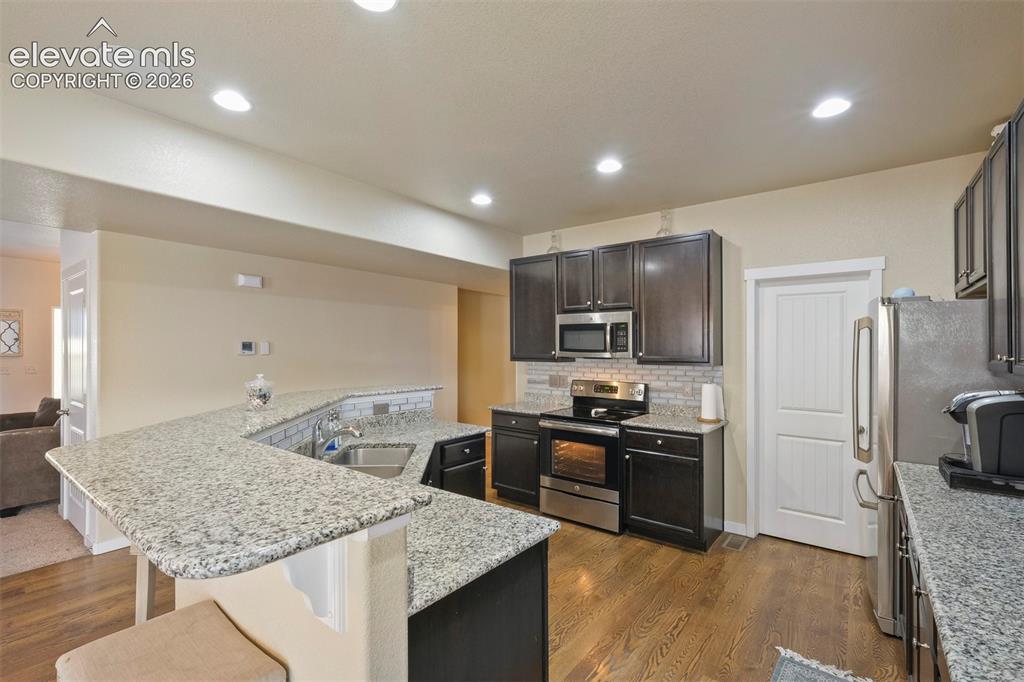 Image 8 of 33: Modern kitchen featuring granite countertops, wood-finish flooring, dark wo