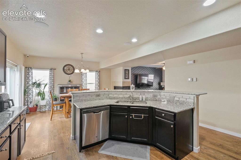 Image 9 of 33: Kitchen island featuring dark cabinetry, stainless steel dishwasher, an und