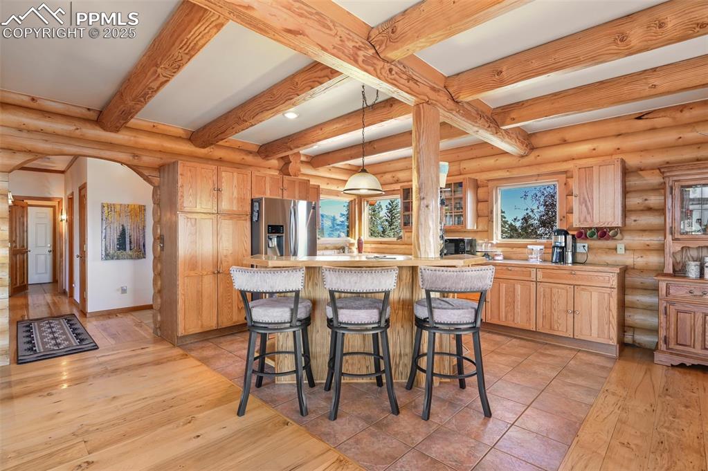 Image 13 of 50: Kitchen with beamed ceiling, light countertops, arched walkways, and stainl