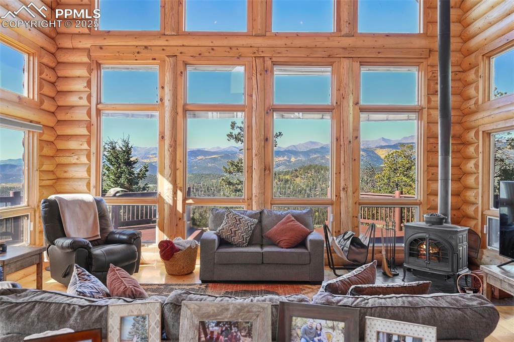 Image 19 of 50: Living area with a towering ceiling, a wood stove, and wood finished floors