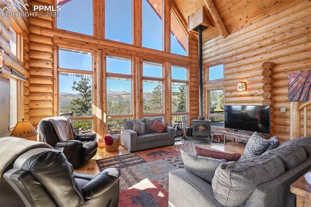 Image 20 of 50: Living room with beamed ceiling, wood finished floors, rustic walls, a wood