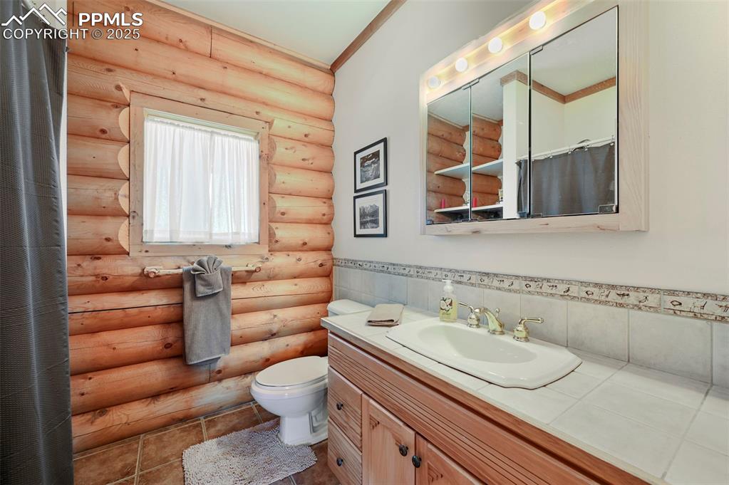 Image 24 of 50: Bathroom featuring crown molding, toilet, curtained shower, vanity, and tas