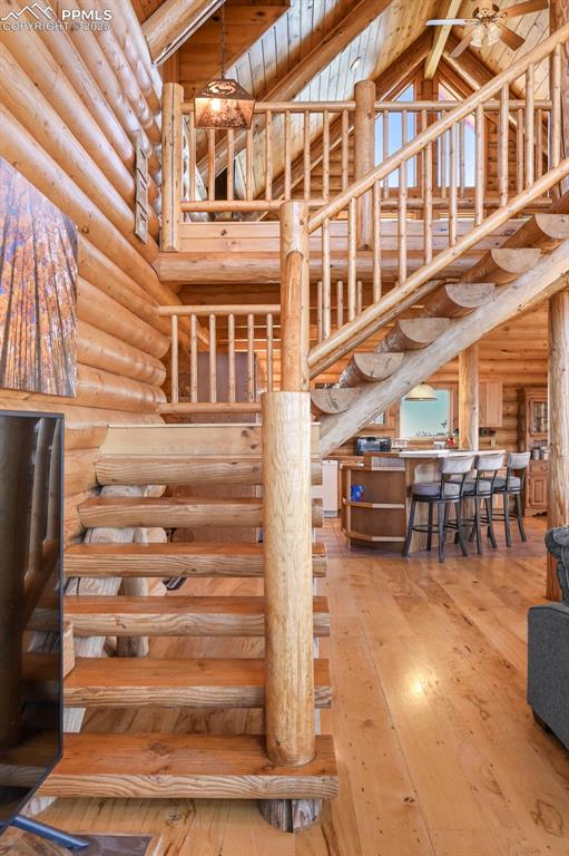 Image 25 of 50: Staircase featuring wood-type flooring, log walls, and high vaulted ceiling