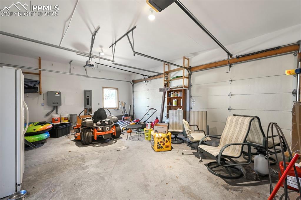 Image 31 of 50: Garage featuring electric panel, a garage door opener, and freestanding ref