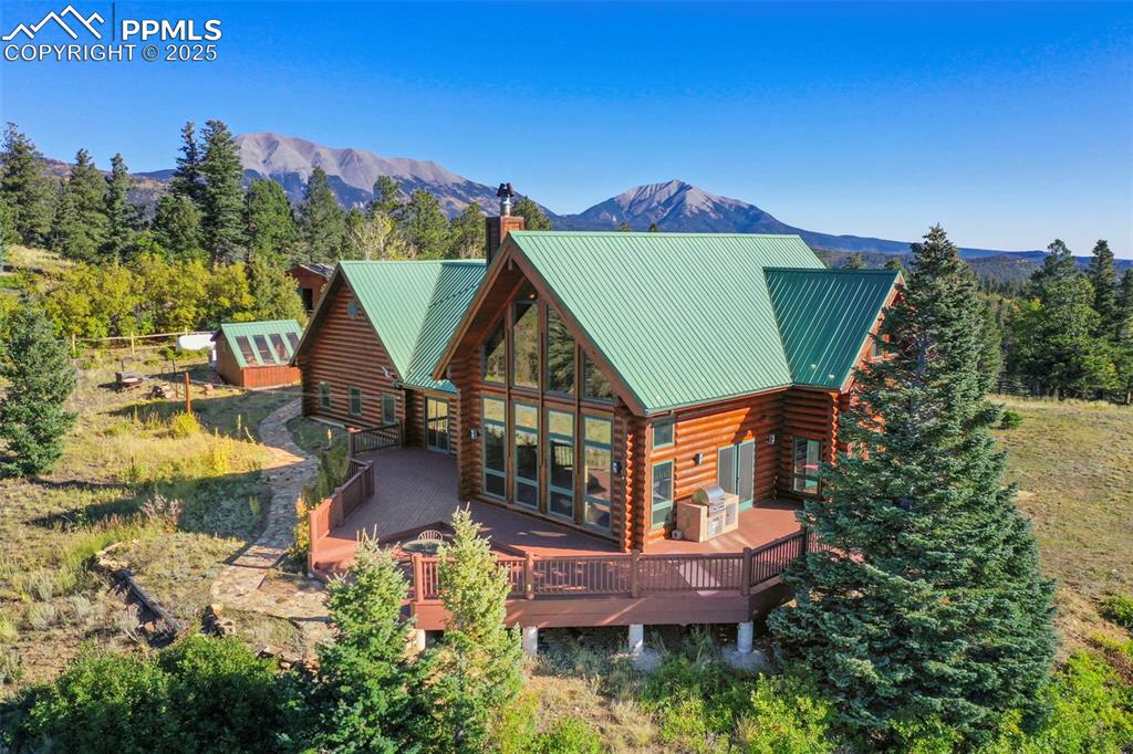Image 38 of 50: Back of property featuring a chimney, a deck with mountain view, metal roof