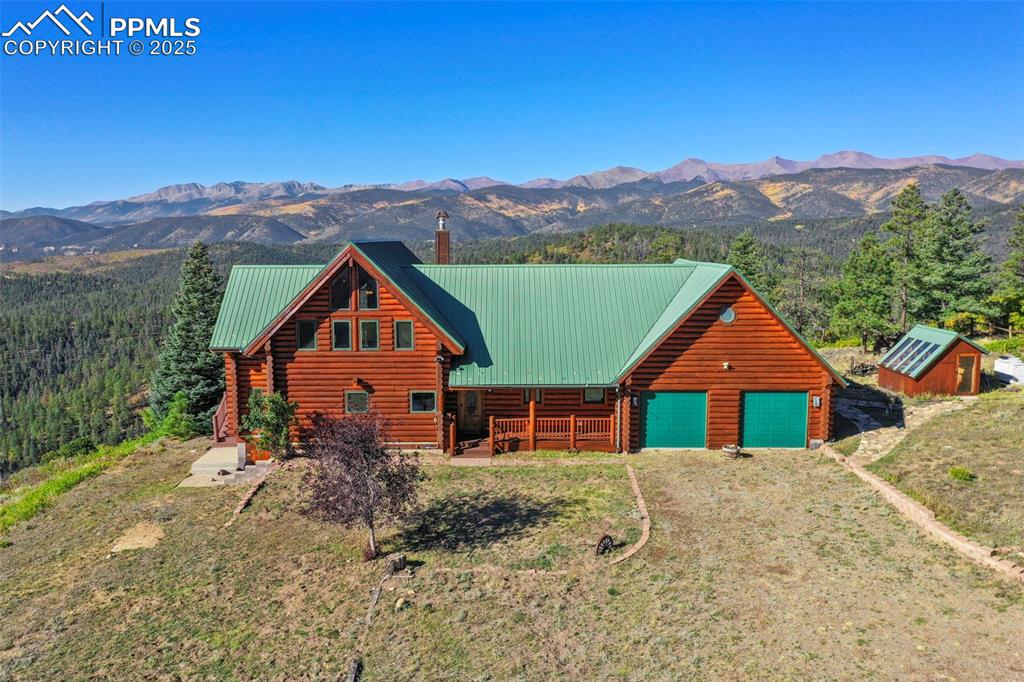 Image 5 of 50: Log home with metal roof, log siding, a mountain view, and driveway