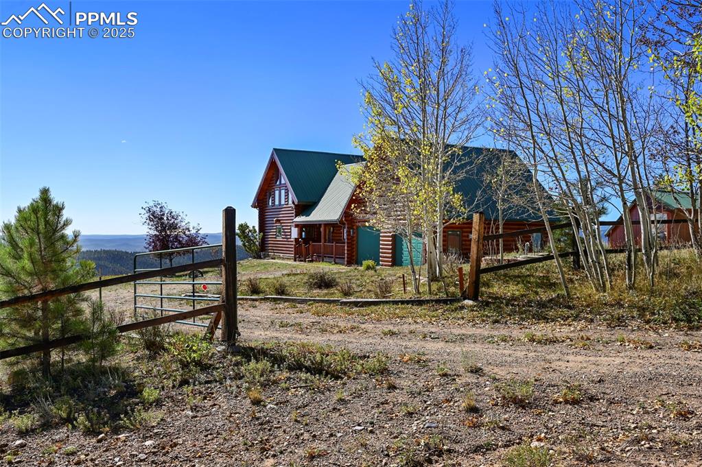 Image 6 of 50: View of side of property with metal roof, fence, and log veneer siding