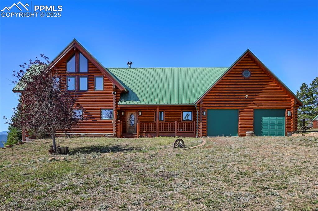 Image 7 of 50: Log-style house featuring an attached garage, metal roof, and log exterior