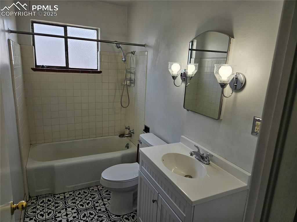Image 11 of 22: Bathroom with toilet, washtub / shower combination, vanity, and tile patter