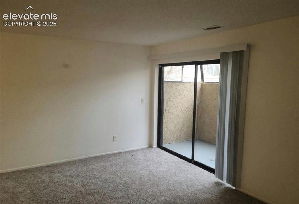 Image 4 of 9: Sliding glass door leading to an outdoor patio with stucco walls