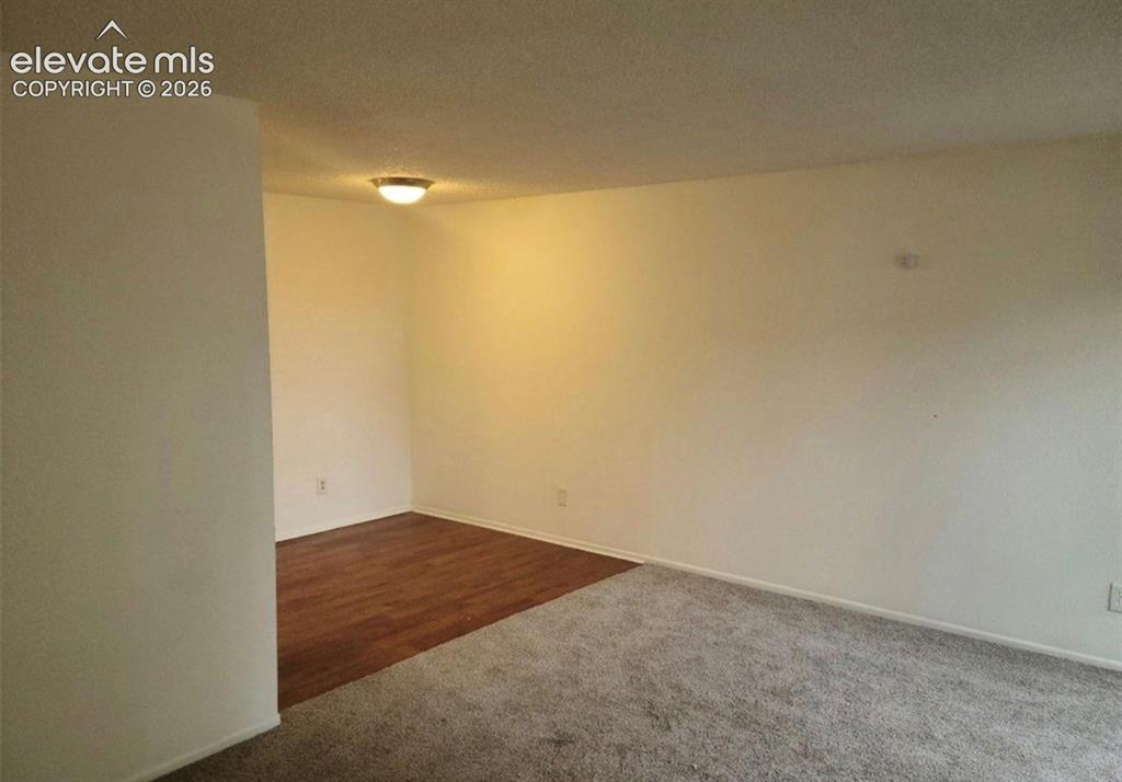 Image 5 of 9: Spacious room featuring neutral wall tones, textured ceiling, and a combina