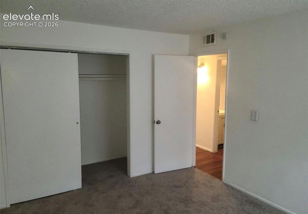 Image 8 of 9: Bedroom featuring a sliding closet door, white walls, and textured ceiling