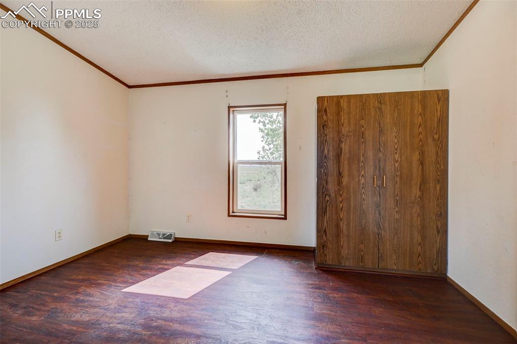 Image 19 of 48: Unfurnished room featuring wood finished floors, crown molding, a textured 
