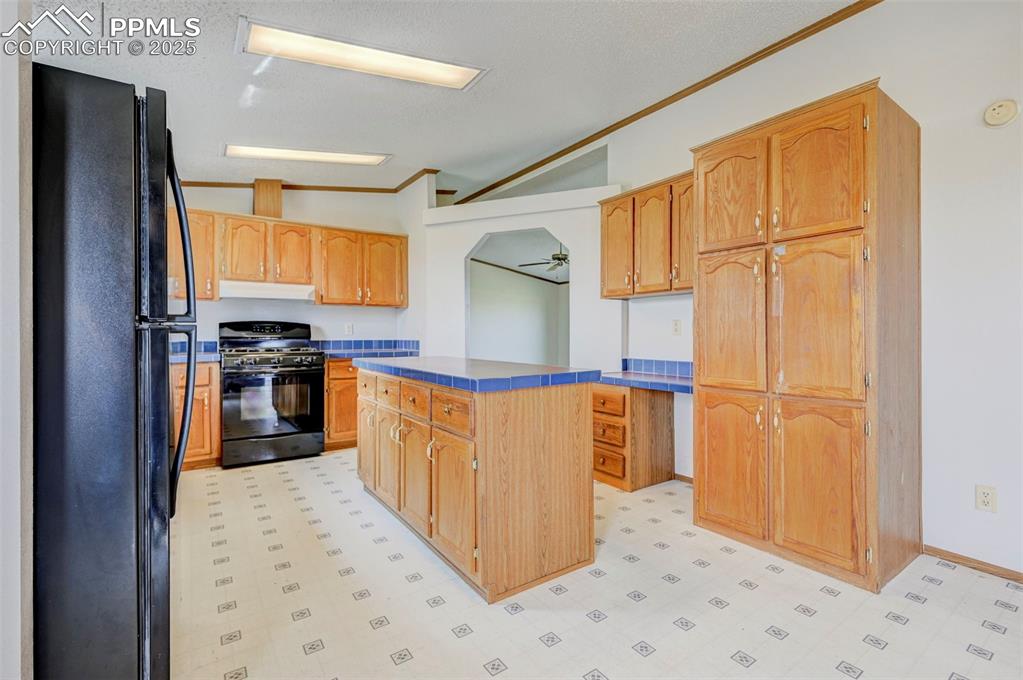 Image 21 of 48: Kitchen with black appliances, under cabinet range hood, light flooring, a 