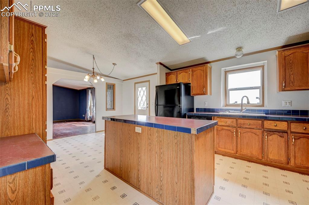 Image 23 of 48: Kitchen with freestanding refrigerator, light flooring, a sink, ornamental 