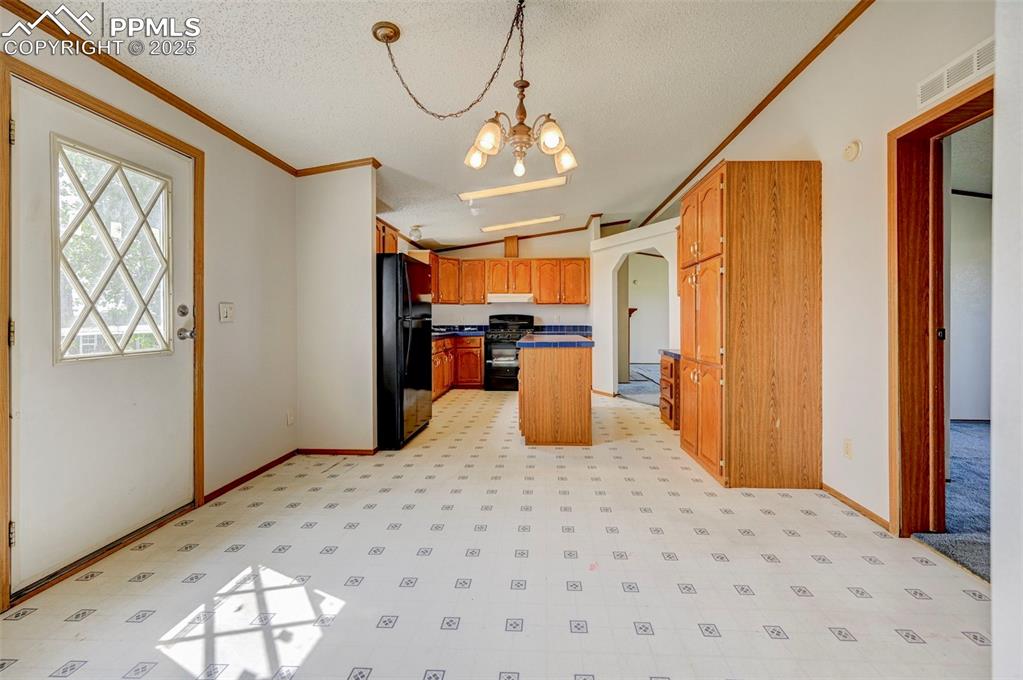 Image 24 of 48: Kitchen featuring black appliances, a textured ceiling, a chandelier, baseb