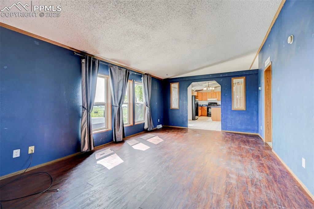 Image 26 of 48: Empty room featuring a textured ceiling, wood finished floors, and baseboar