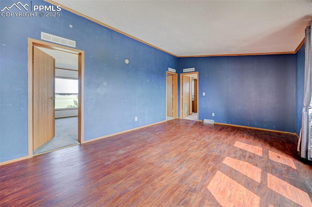 Image 28 of 48: Unfurnished room with wood finished floors, a textured ceiling, baseboards,