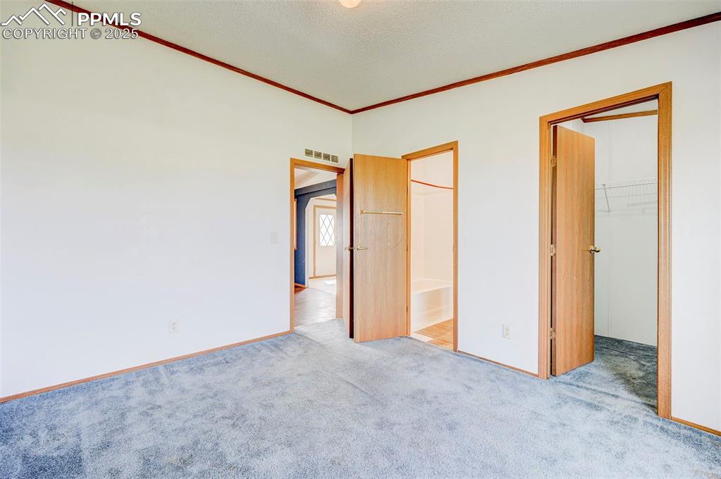Image 31 of 48: Unfurnished bedroom with a spacious closet, ornamental molding, carpet floo