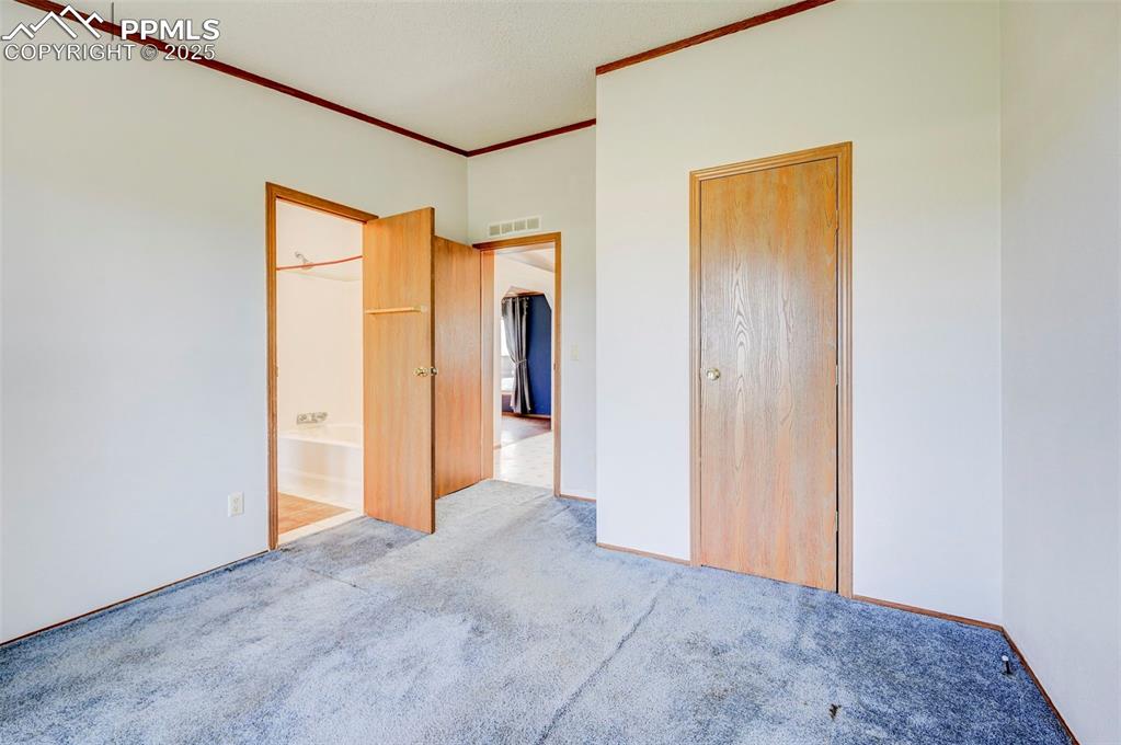 Image 35 of 48: Unfurnished bedroom featuring carpet, crown molding, and connected bathroom