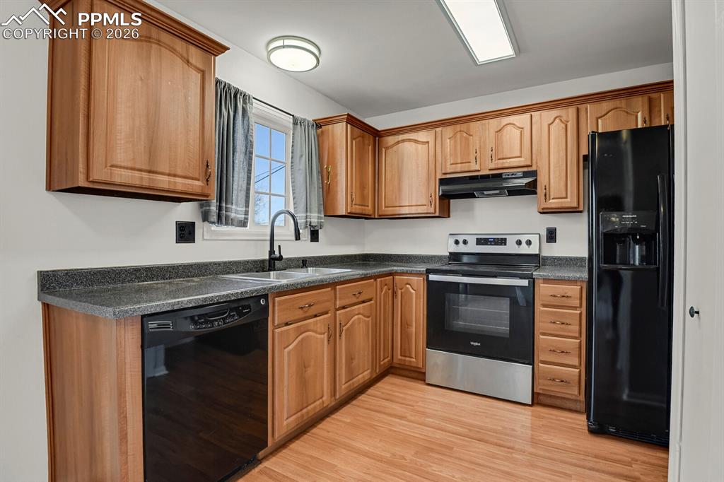 Image 11 of 31: Kitchen featuring black appliances, light wood-style floors, and wood finis