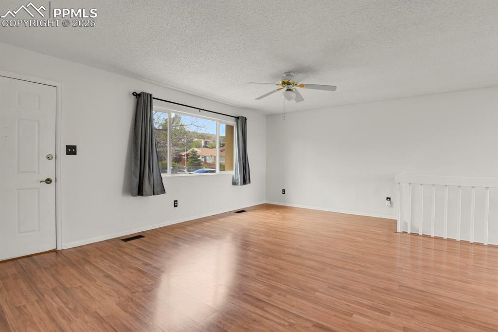 Image 6 of 31: Empty room featuring light wood finished floors, ceiling fan, and a texture